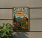 A vintage-style metal sign for Santa Fe National Forest in New Mexico, featuring a scenic mountain landscape with pine trees and a sign for the U.S. Forest Service.