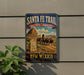 A vintage-style metal sign for the Santa Fe Trail in New Mexico, featuring an illustration of a wagon train traveling through the desert landscape.