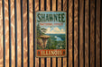 A vintage metal sign for Shawnee National Forest in Illinois, featuring a scenic landscape with a river and mountains.
