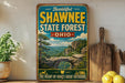 A vintage-style sign for Shawnee State Forest in Ohio, featuring a scenic landscape with a bridge and mountains in the background.