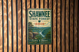 A vintage metal sign for Shawnee State Forest, Ohio, featuring a scenic landscape with a river and mountains.