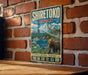 A vintage-style metal sign with the text "SHIRETOKO JAPAN" and an illustration of a bear in front of a mountain landscape.