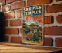 A vintage-style sign for the Shrines and Temples of Nikko, Japan, featuring an illustration of a temple surrounded by trees and a bridge.