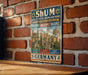 a vintage-style sign with illustrations of buildings and text, mounted on a brick wall.