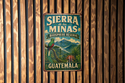 A vintage-style metal sign with the text "SIERRA de las MINAS BIOSPHERE RESERVE GUATEMALA" and an illustration of a colorful bird perched on a tree.