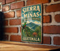 A vintage-style sign for Sierra de las MINAS Biosphere Reserve in Guatemala, featuring a lush green landscape with a colorful bird and tropical plants.