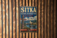 A vintage metal sign for Sitka National Historical Park in Alaska, featuring a scenic image of the park and its surroundings.