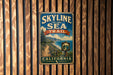A vintage-style metal sign with the text "SKYLINE TO THE SEA TRAIL" and "CALIFORNIA" is displayed on a wooden wall.