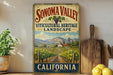 a vintage-style sign for Sonoma Valley, California, with a vineyard landscape and mountains in the background. The sign is mounted on a wall, and there are some kitchen utensils and a potted plant in the foreground.