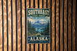 A vintage-style metal sign with the text "SOUTHEAST STATE FOREST WILD LAND. GREAT ADVENTURES. ALASKA" is displayed on a wooden wall.