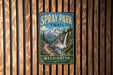 A vintage metal sign for the Spray Park Trail in Washington, featuring a mountain landscape with a waterfall.