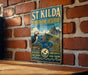 A vintage-style metal sign for St Kilda Bioscape Reserve, featuring a puffin bird and a scenic landscape.