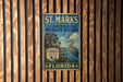 A vintage-style metal sign for St. Marks National Wildlife Refuge in Florida, featuring a bird and palm trees, mounted on a wooden wall.