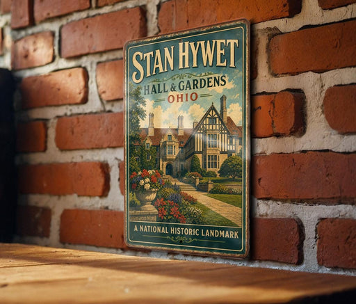 A vintage-style metal sign for "Stan Hywet Hall & Gardens" in Ohio, featuring a brick wall and a garden scene.