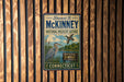 A vintage-style metal sign with the name "Stevast B. McKinney" and the title "National Wildlife Refuge" is displayed on a wooden wall.