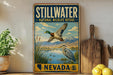 A vintage-style metal sign for Stillwater National Wildlife Refuge in Nevada, featuring a painting of ducks and mountains in the background.