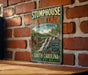 A vintage metal sign for Stumphouse Mountain Heritage Preserve in South Carolina, featuring a scenic illustration of a waterfall and a wooden cabin.