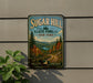A vintage-style sign for Sugar Hill State Forest in New York, featuring a scenic landscape with pine trees, a winding road, and a body of water.