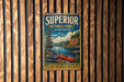 A vintage metal sign for Superior National Forest in Minnesota, featuring a scenic image of a canoe on a lake surrounded by pine trees and mountains.