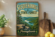 A vintage-style sign for Susquehannock State Forest in Pennsylvania, featuring a scenic landscape with a river and mountains.