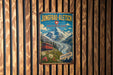 A vintage-style metal sign with a mountain landscape and a red train, mounted on a wooden wall.