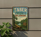 A vintage metal sign for Taber State Forest, Delaware, featuring a scenic landscape with a lake and pine trees.
