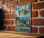 A vintage-style metal sign for the Tahoe Rim Trail in California, featuring a scenic mountain landscape and a trail marker.