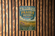 A vintage metal sign for Tallgrass Prairie Preserve in Oklahoma, featuring a scenic landscape with a bird in flight and a field of flowers.
