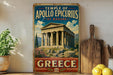 A vintage-style sign for the Temple of Apollo Episcus in Bassae, Greece, featuring an illustration of the ancient Greek temple against a cloudy sky.