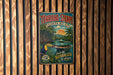 A vintage-style metal sign with a tropical landscape and a bird, hanging on a wooden wall.