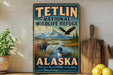 A vintage-style sign for Teltlin National Wildlife Refuge in Alaska, featuring wildlife such as a moose, eagle, and loon.