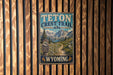 A vintage-style metal sign for the Teton Crest Trail in Wyoming, featuring a mountain landscape and trail path.
