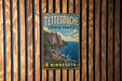 A vintage metal sign for Tettegouche State Park in Minnesota, featuring a scenic landscape with a cliff overlooking the ocean.