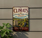 A vintage-style metal sign with the text "The Climats" and "Terroirs of Burgundy" is displayed on a wall, featuring an illustration of a vineyard landscape with grapes and a gravestone.