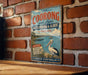 A vintage-style metal sign with text and an illustration of a bird, mounted on a brick wall.
