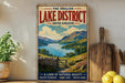A vintage-style metal sign advertising the Lake District, United Kingdom, featuring a scenic landscape with mountains, lakes, and a wooden fence.