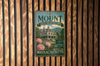 A vintage metal sign for "The Mount Edith Wharton's Home" in Massachusetts, featuring a large house surrounded by trees and pink flowers.