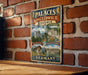 a vintage metal sign with illustrations of various landmarks and buildings, including a castle, a palace, and a church, all set against a brick wall.