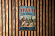 A vintage-style metal sign with the text "The TRULLI of ALBEROBELLO ITALY" and an illustration of a village, hanging on a wooden wall.