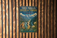 a vintage-style metal sign with a mountain landscape and a monkey, mounted on a wooden wall.
