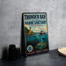 A vintage-style metal sign for the Thunder Bay National Marine Sanctuary in Michigan, featuring an illustration of a lighthouse, boats, and underwater scenery.