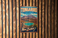 A vintage metal sign for Tongarro National Park in New Zealand, featuring a scenic landscape with mountains, a lake, and a waterfall.