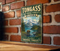 A vintage-style metal sign for Tongass National Forest in Alaska, featuring a scenic landscape with a bear and mountains in the background.