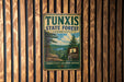 A vintage metal sign for Tunxis State Forest in Connecticut, featuring a scenic landscape with pine trees and a river.