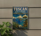 A vintage-style sign for the Tuscan Islands Biosphere Reserve in Italy, featuring a scenic landscape with mountains, a coastline, and a small island with a palm tree.