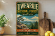 A vintage-style sign for the Uwharrie National Forest, featuring a scenic landscape with mountains, pine trees, and a river.
