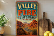 A vintage-style sign for Valley of Fire State Park in Nevada, featuring a desert landscape with mountains and a winding road.