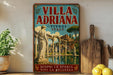 A vintage-style poster of the villa "Villa Adriana" in Italy, featuring a classical architectural scene with a fountain and statues.
