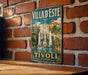 A vintage-style metal sign with the text "Villa d'Este" and "Tivoli Italy" displayed on a brick wall.