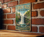 A vintage-style sign for Virgin Falls, a state natural area in Tennessee, is displayed on a brick wall.